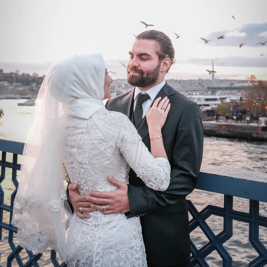 İstanbul’da deniz kenarında sarılan gelin ve damat, arkalarında martılar ve şehir silüeti